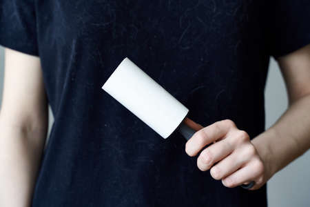 An unrecognizable woman cleans a black t-shirt with a clothes roller.の写真素材
