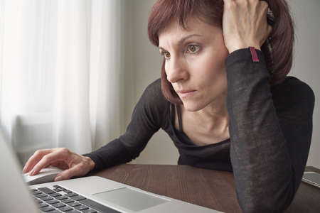 Woman is looking for information on Internet, nervous, focused. Concept for digital addiction