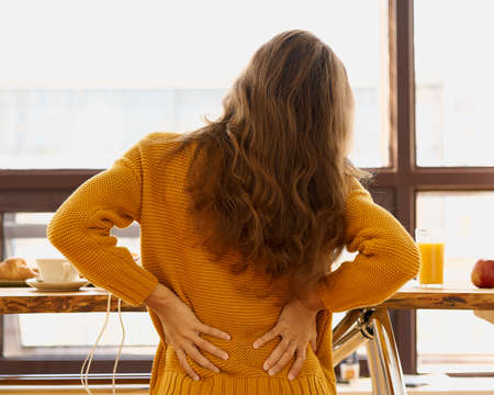 Back view of faceless young woman touching back feeling backache, discomfortの写真素材