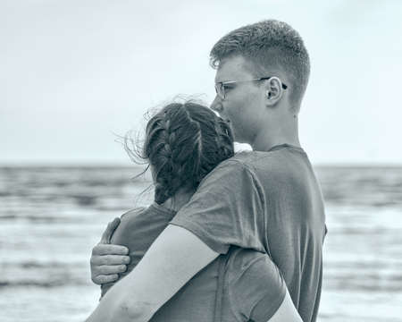 Picnic on beach with food and drinks. Young boy and girl embrace. Black and whiteの写真素材