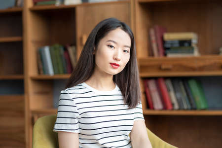 Portrait of beautiful young Asian woman in striped t shirt sitting in chair