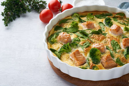 Egg-based frittata, omelette with salmon, broccoli and spinach. Italian dish, crustless quiche with eggs, fish and vegetables. Mediterranean ketogenic healthy diet. Side view, copy spaceの写真素材