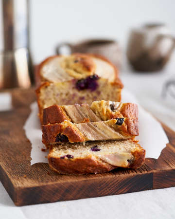 Banana bread, slice of cake with banana and blueberries. Morning breakfast with coffee on light gray...