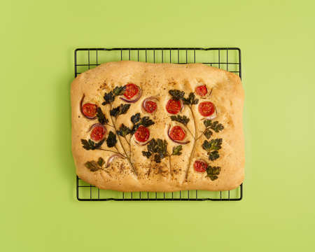 Food art. Focaccia, pizza, flat bread with vegetables, tradition italian cuisine. Flatbread with tomatoes, parsley and onion on green lime monochrome color bright backgroundの写真素材