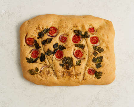 Food art. Focaccia, pizza, flat bread with vegetables, tradition italian cuisine. Flatbread with tomatoes, parsley and onion. Single object, trendy concept. Top view, white gray tableの写真素材