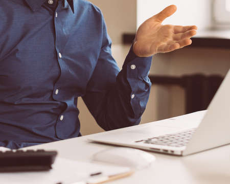 Cropped faceless man professional call center operator looking at laptop screen and talking while...