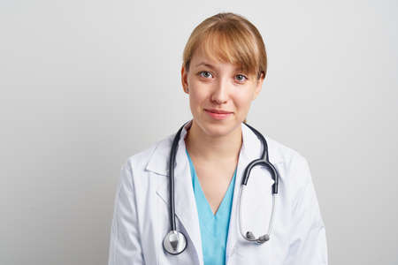 Young trustworthy woman healthcare worker with stethoscope and in white coat looking at camera and...