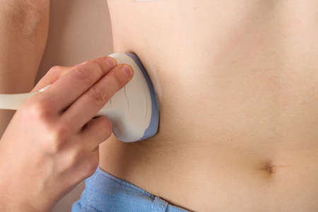 Closeup of anonymous doctor doing ultrasound diagnostics of patient right kidney prolapse. Scanning...