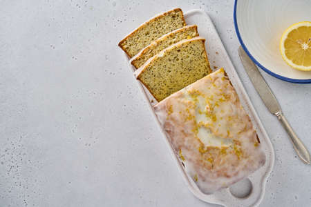 Horizontal of sliced lemon bread with poppy seeds, white icing and citrus zest. Served delicious...