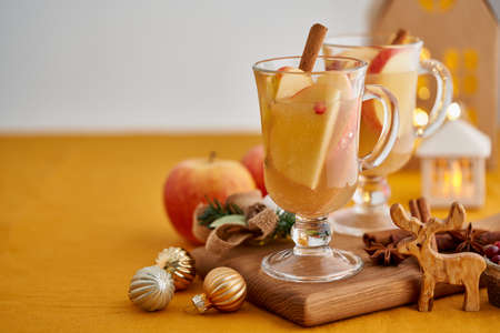 Two glasses of hot christmas winter apple gluhwein. Alcohol white mulled wine with cinnamon, cranberry. Apple cider. Selective focus, blurred christmas decor background, copy spaceの写真素材