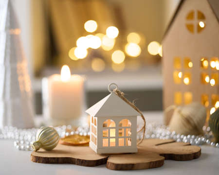 Cozy winter atmosphere. Candles, garland, beads. Christmas decor. Family seasonal wintertime interior. Boxes and houses. Selective focus, blurred background, bokehの写真素材