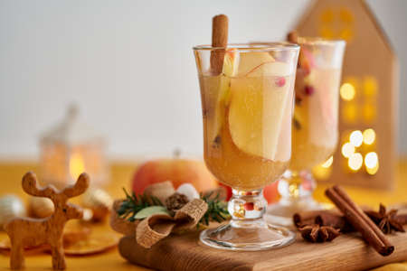 Winter white mulled wine punch. Xmas decor. Colorful grog beverage. Christmas apple cider toddy. Seasonal alcohol winter drink. Advent blurred bokeh garland background, selective focus, copy spaceの写真素材
