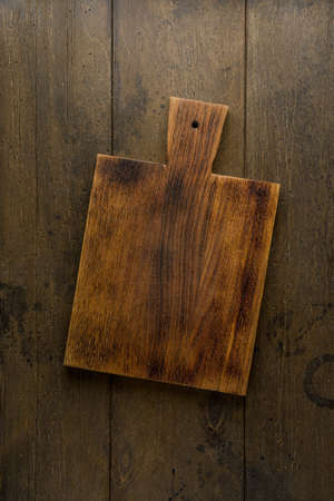 Old wooden chopping board. Food background. Overhead. Vertical. Dark plankの写真素材