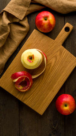 Peeled red apples on wooden cutting board. Food background verticalの写真素材