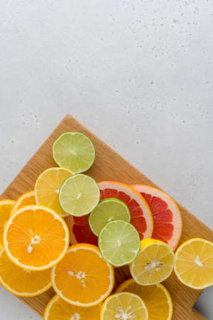 Citrus composition on chopping board. Many halved lemons, limes, grapefruits. Vertical, copy spaceの写真素材