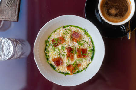 Bulgur porridge with bacon and greenery. Healthy food in restaurant. Modern breakfast not at homeの写真素材