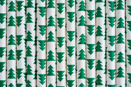 Closeup of cocktail paper straws with green trees design. Recyclable organic tubes
