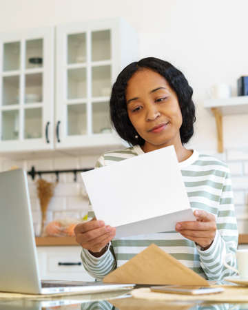 Young african-american female opening and reading letter. Concept of receiving mail correspondenceの写真素材