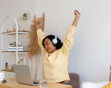 African-american female stretching after working on laptop. Listening to music in earphonesの写真素材