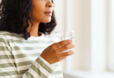 Cropped African-American female drinking glass of water. Refreshing start of dayの写真素材