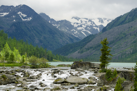 The beautiful landscape of the river running on stones among mountains and the woodの写真素材