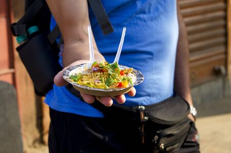 The man holds in hand a plate with street Indian foodの写真素材