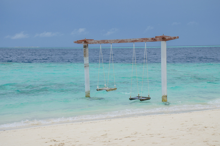 beach with white sand and a swing over the oceanの写真素材