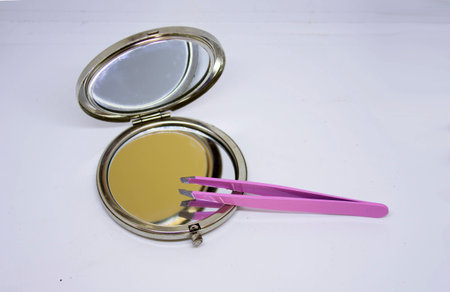 Pink tweezers and mirror for eyebrow designの写真素材