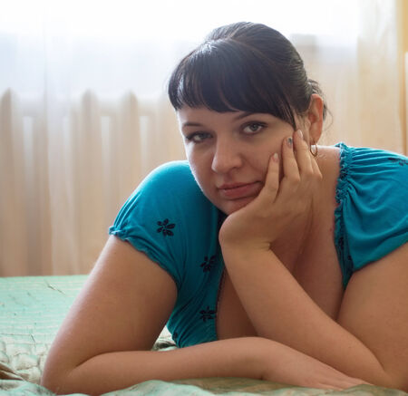 Portrait of a cute plump girl propped his head on his hand in the soft warm tonesの写真素材