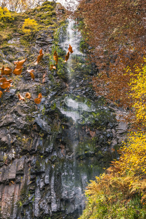 Dramatic Waterfall Cascading Over Basalt Rock Columns in Autumnの写真素材