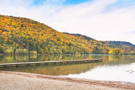 Tranquil Autumn Lake Surrounded by Colorful Mountains and Forestの写真素材