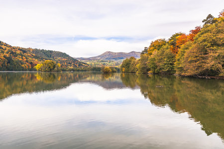 Tranquil Autumn Lake Surrounded by Colorful Mountains and Forestの写真素材