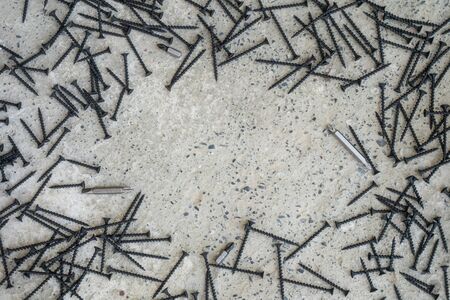 A lot of black metal screws on the concrete surfaceの写真素材