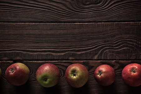 Row of several red apples on a wooden surfaceの写真素材