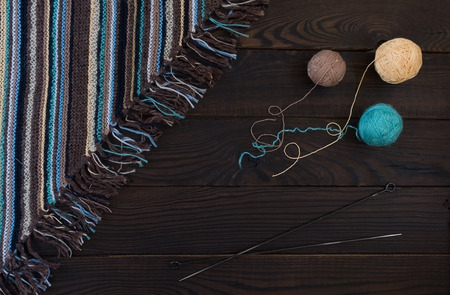 Fragment of handmade knitted fabric, knitting needles and balls