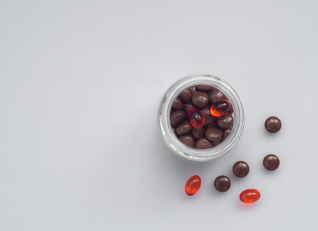 Different pills spill out of a glass jar on light surfaceの写真素材
