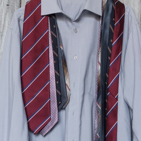 A mens shirt with a five ties hanging on a hanger on a backgrouの写真素材