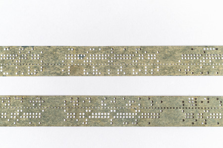 Strips of old punched tape on white surfaceの写真素材
