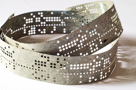 Strips of old punched tape on white surfaceの写真素材