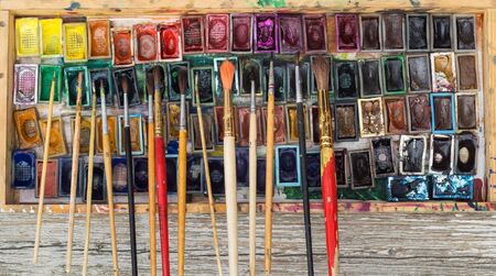 Box with watercolors and brushes on wooden surfaceの写真素材