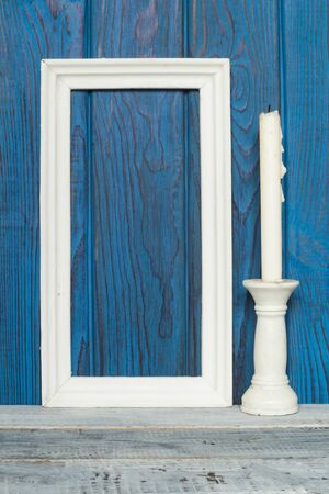 White frame and a candle on a background of blue boardsの写真素材