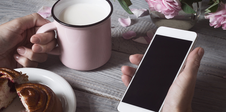 Cup of milk and the phone in handsの写真素材