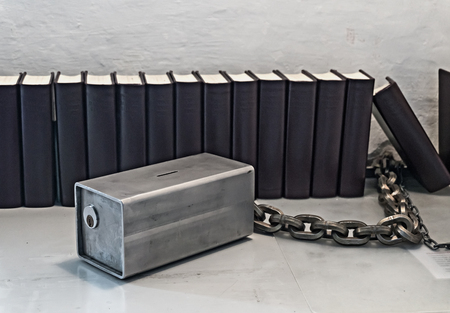 A row of books near a white wall and a metal money boxの写真素材