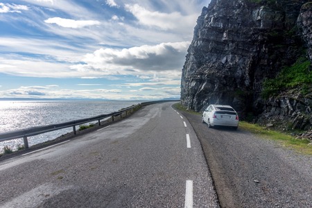 Road and white car near the sea and rocky mountains, Finnmark, Norwayの写真素材