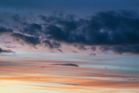 Gray, blue and orange clouds at sunsetの写真素材