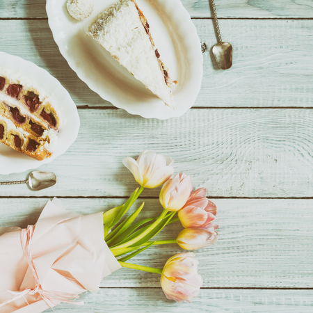 A cake with cherries and pink tulips on a white wooden tableの写真素材