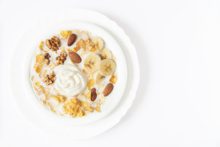 Oat flakes and nuts with milk on a white plateの写真素材