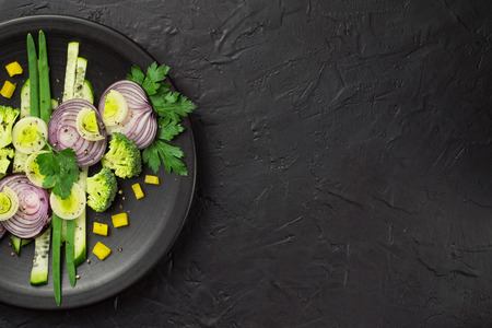 Fresh vegetables on a black plate on a dark tableの写真素材