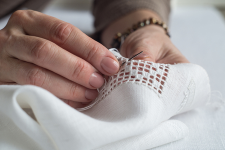 Hands of a woman embroidering a geometric ornament