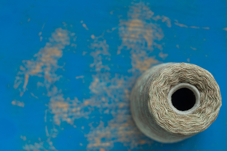 Coil with gray threads on a blue wooden surface